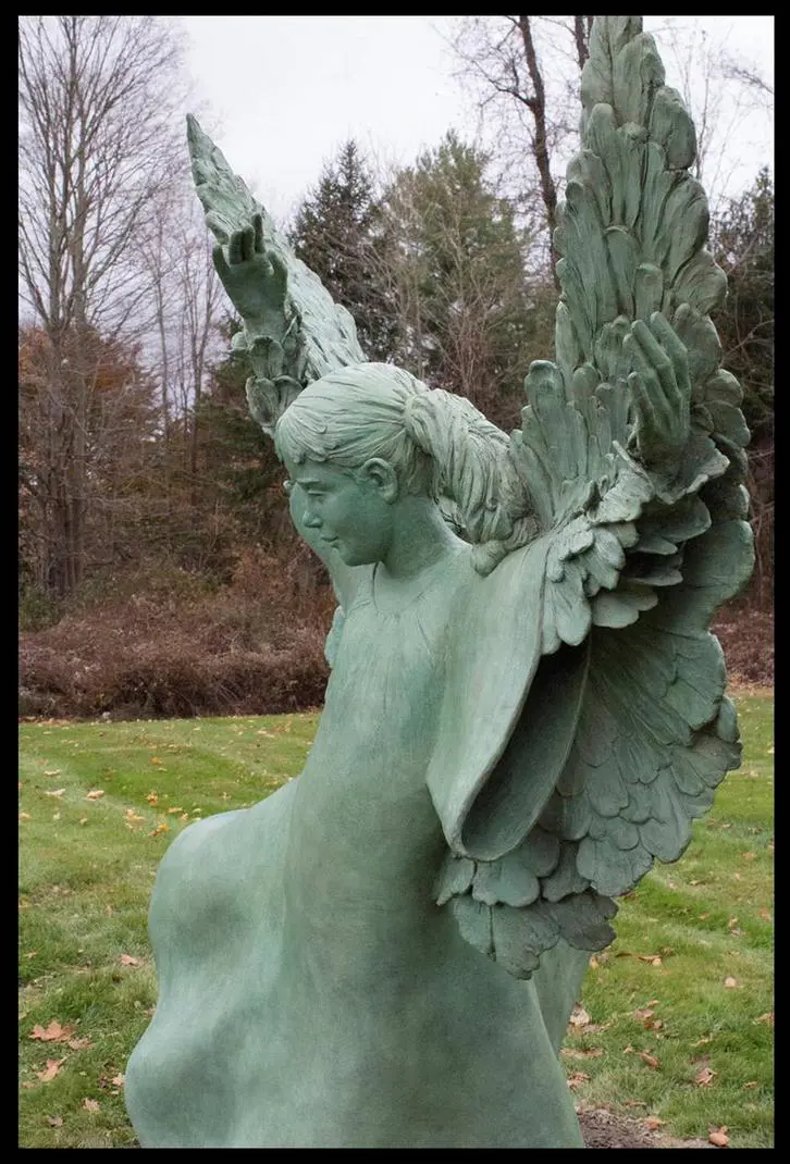 A statue of an angel in the grass.