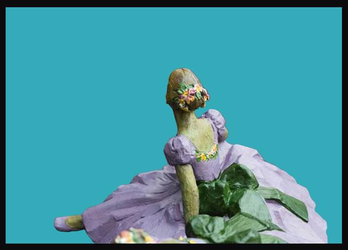 A green and purple doll sitting on top of a blue background.