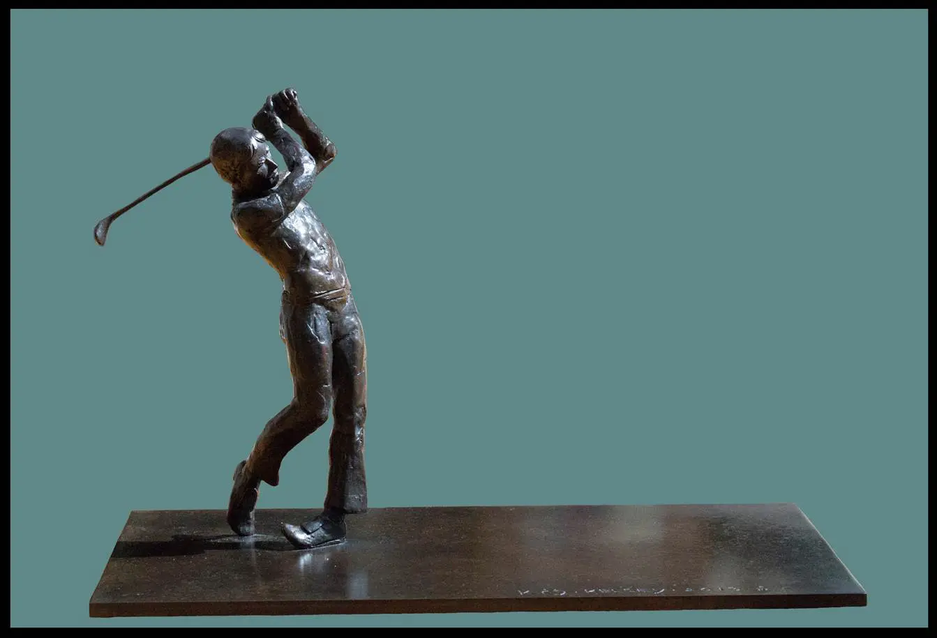 A metal sculpture of a man swinging at the golf ball.